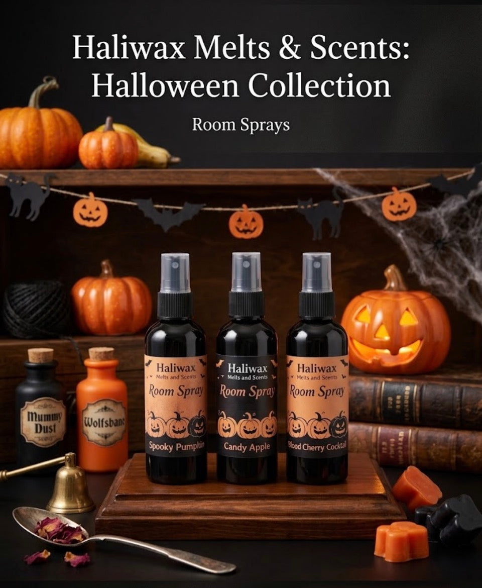 Three Haliwax Halloween room spray bottles labelled Spooky Pumpkin, Candy Apple and Blood Cherry Cocktail displayed on a wooden shelf surrounded by jack-o-lanterns, pumpkins, cobwebs and Halloween decorations.