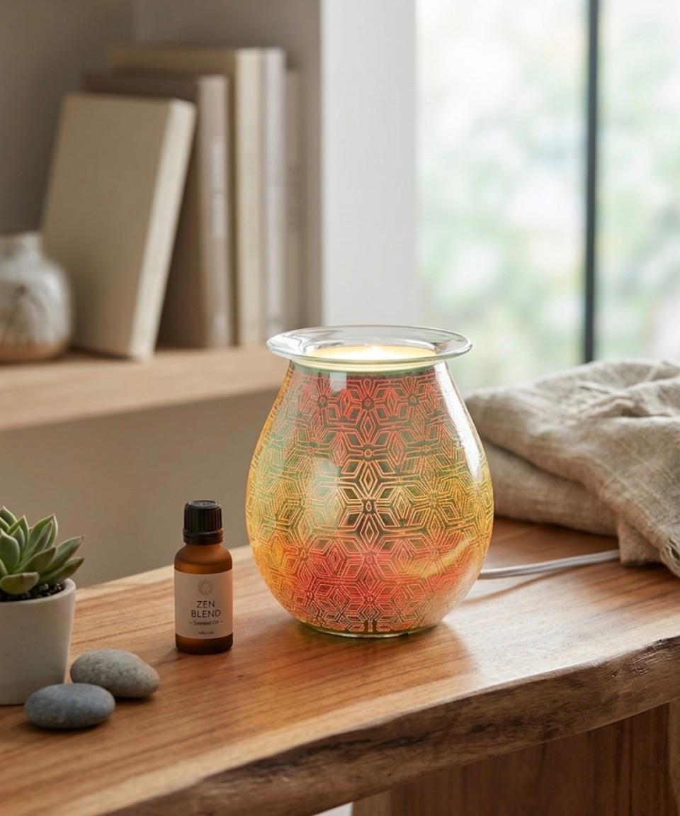 Geometric Flower Electric Oil Burner glowing in warm amber tones on a wooden surface with zen blend oil and succulents
