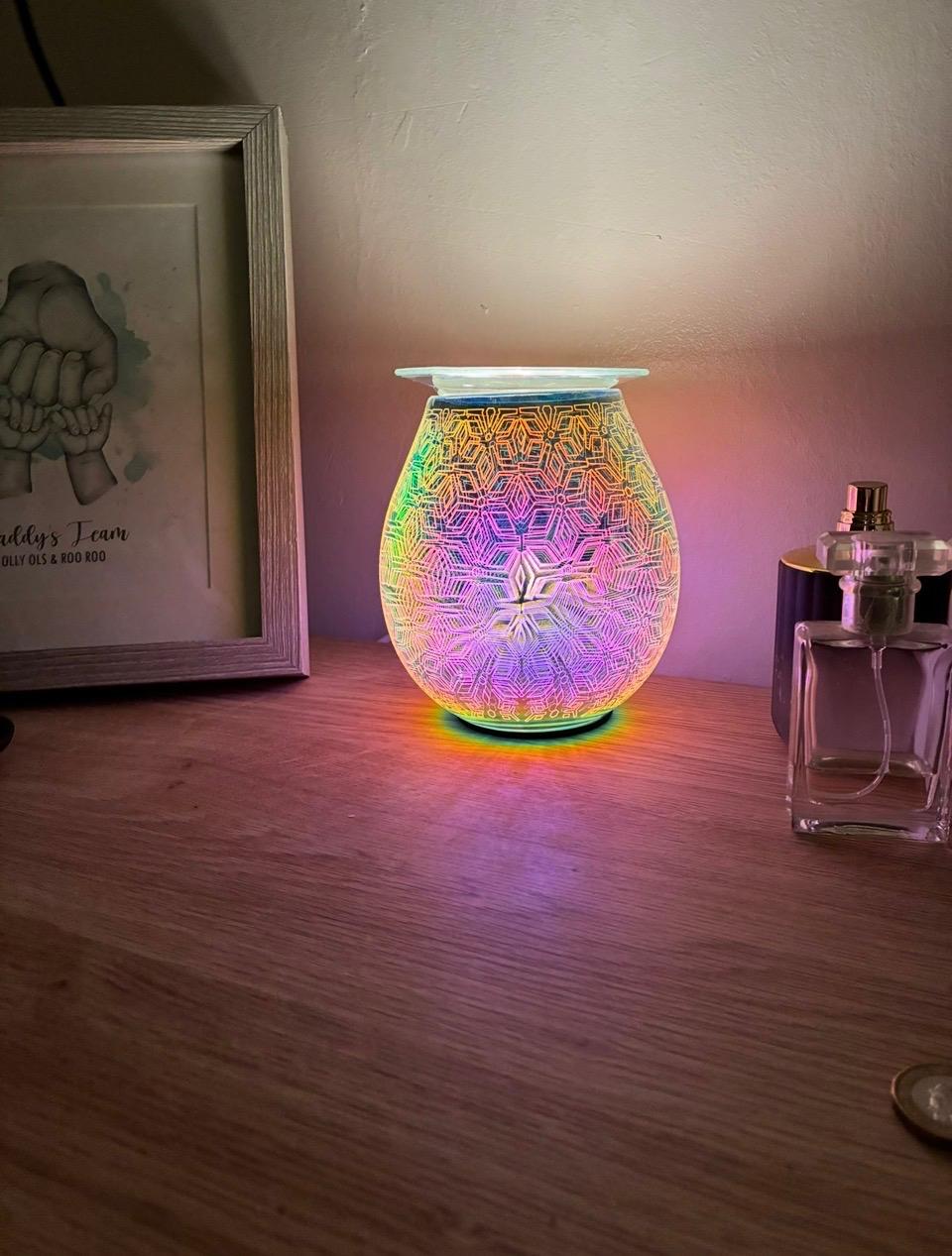 Geometric Flower Electric Oil Burner glowing with multicolour light next to a family photo frame